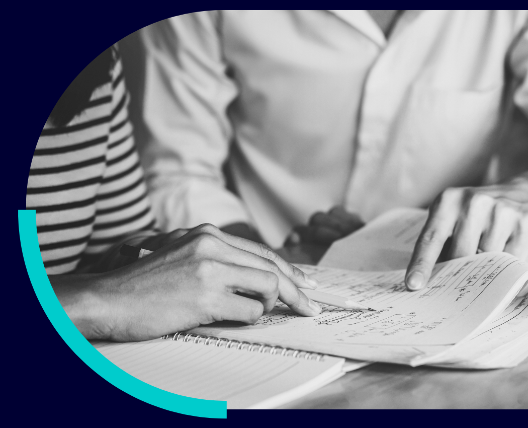Two professionals writing in a workbook