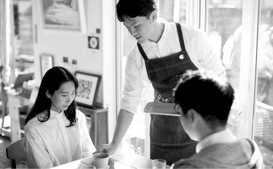 Man serving coffee at a cafe to customers