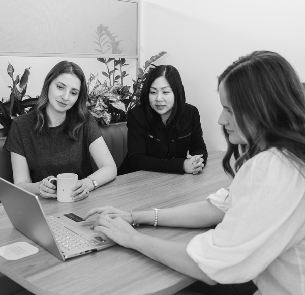 Three women looking at laptop black and white