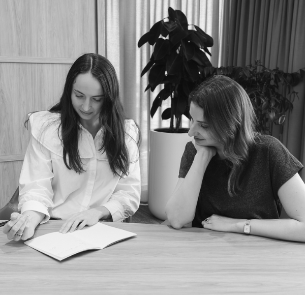 Two women looking at notebook black and white